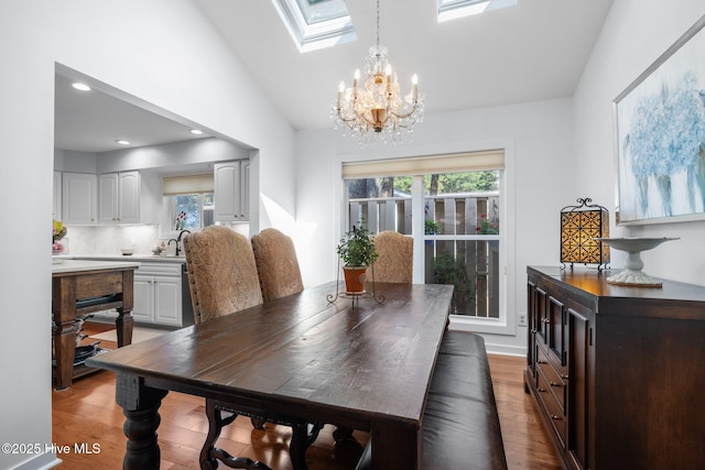 111 Mcginnis Dr, Pine Knoll Shores, NC 28512 - dining area featuring light wood-style flooring, a chandelier, healthy amount of natural light, a skylight, and lofted ceiling