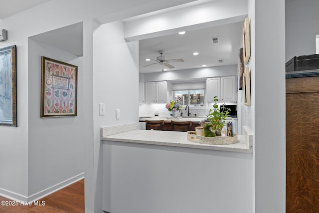 111 Mcginnis Dr, Pine Knoll Shores, NC 28512 - kitchen with white cabinetry, ceiling fan, dark wood-style flooring, recessed lighting, and light stone countertops