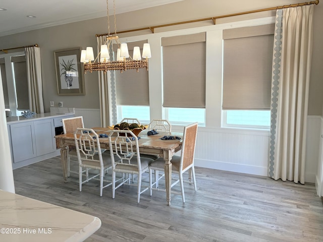 23 Leland St, Ocean Isle Beach, NC 28469 - dining room with light wood-style flooring, ornamental molding, a wainscoted wall, and a chandelier