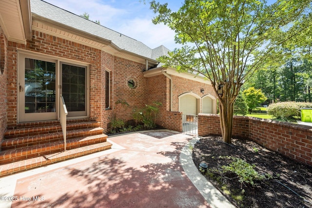 7006 Club House Dr, New Bern, NC 28562 - doorway to property featuring brick siding, roof with shingles, a gate, and a garage