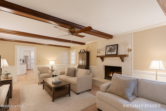 5025 Netherwood Rd, Rocky Mount, NC 27803 - living room featuring beam ceiling, ceiling fan, a wainscoted wall, a brick fireplace, and crown molding