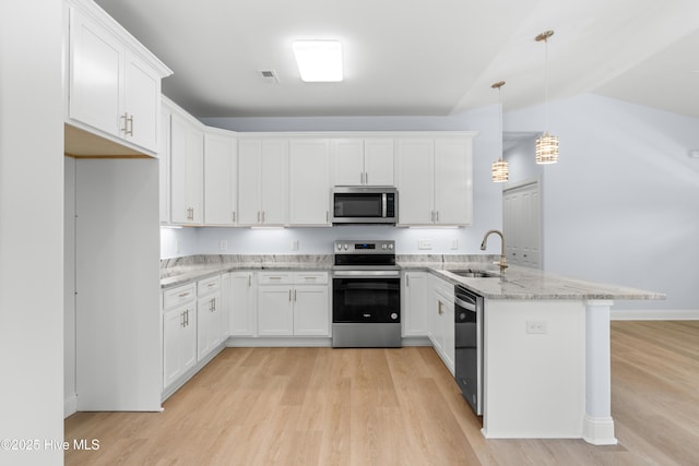 1990 Salisbury Rd, Southport, NC 28461 - kitchen featuring appliances with stainless steel finishes, a peninsula, light wood-type flooring, white cabinetry, and lofted ceiling