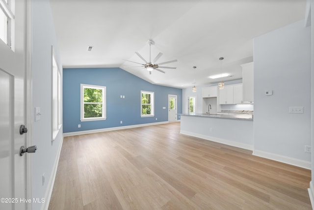 1990 Salisbury Rd, Southport, NC 28461 - unfurnished living room with a ceiling fan, light wood-type flooring, and vaulted ceiling