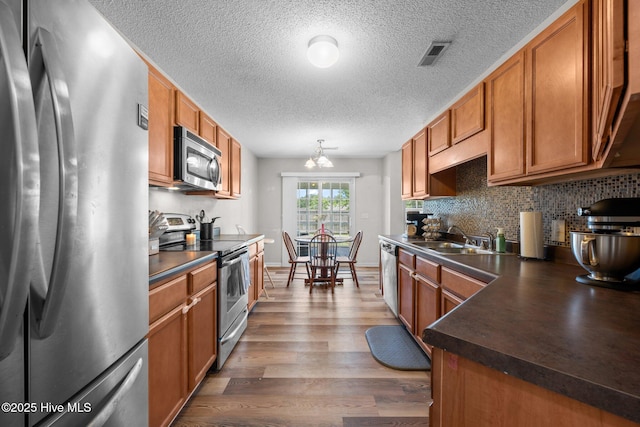 2950 Judge Manly Dr, New Bern, NC 28562 - kitchen with stainless steel appliances, dark countertops, wood finished floors, brown cabinetry, and decorative backsplash