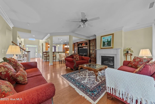 90 Shadow Creek Ct, Pinehurst, NC 28374 - living room featuring wood finished floors, ceiling fan, a glass covered fireplace, crown molding, and stairs