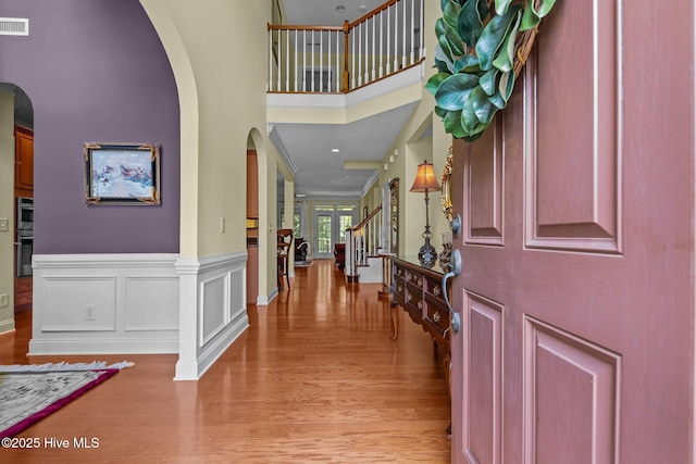 90 Shadow Creek Ct, Pinehurst, NC 28374 - foyer entrance featuring arched walkways, a high ceiling, light wood finished floors, stairway, and wainscoting