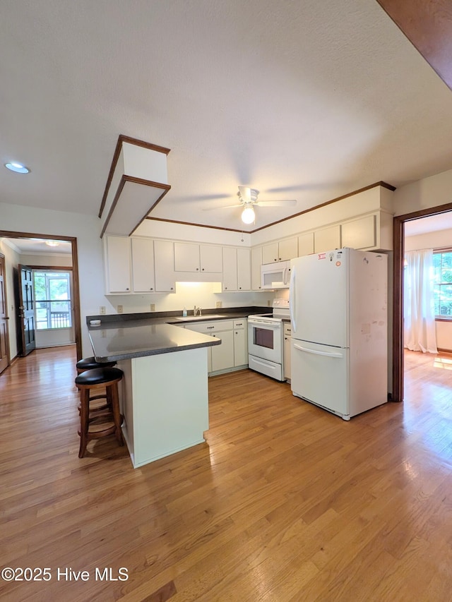 106 Brown Bark Rd, West End, NC 27376 - kitchen featuring white appliances, a peninsula, healthy amount of natural light, and dark countertops