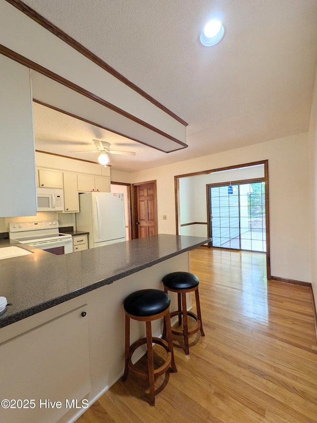 106 Brown Bark Rd, West End, NC 27376 - kitchen featuring white appliances, white cabinetry, a peninsula, light wood-type flooring, and a breakfast bar