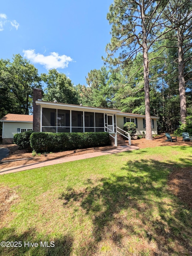 106 Brown Bark Rd, West End, NC 27376 - view of front of house with a sunroom, a chimney, and a front lawn