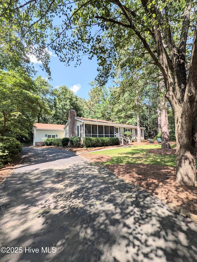 106 Brown Bark Rd, West End, NC 27376 - view of front of property with driveway, a sunroom, and a chimney