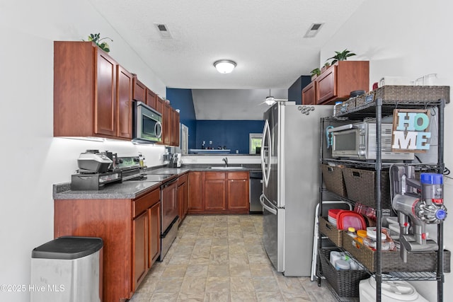 110 Whiteleaf Dr, Jacksonville, NC 28546 - kitchen with stainless steel appliances, dark countertops, ceiling fan, stone finish flooring, and a textured ceiling