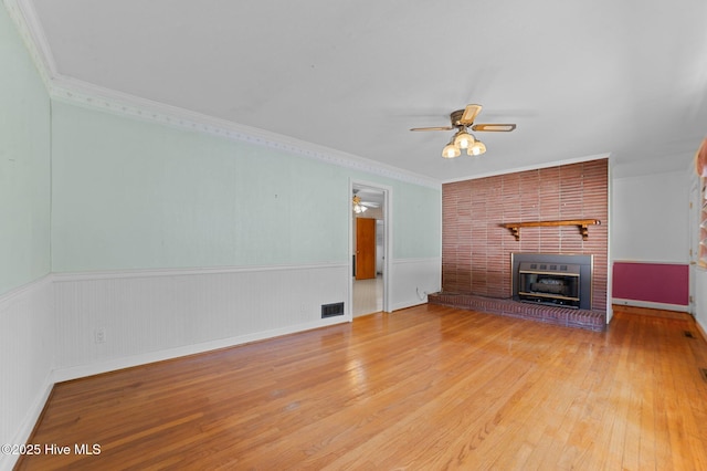 1603 Laurel St, Goldsboro, NC 27530 - unfurnished living room featuring ceiling fan, wood finished floors, a brick fireplace, a wainscoted wall, and crown molding