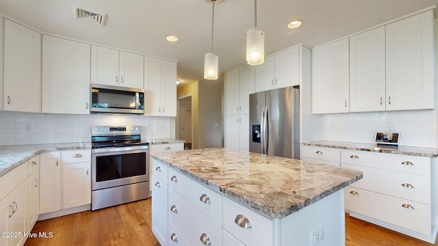 5410 Trade Winds Rd, New Bern, NC 28560 - kitchen with stainless steel appliances, a center island, decorative backsplash, light wood-type flooring, and light stone counters