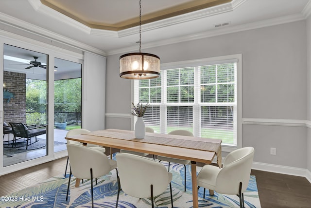 2233 Whiskey Branch Dr, Wilmington, NC 28409 - dining room with dark wood-style floors, a tray ceiling, healthy amount of natural light, a ceiling fan, and ornamental molding
