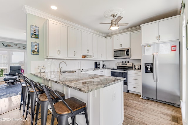 1726 W Beach Dr, Oak Island, NC 28465 - kitchen with stainless steel appliances, a peninsula, light stone countertops, crown molding, and ceiling fan