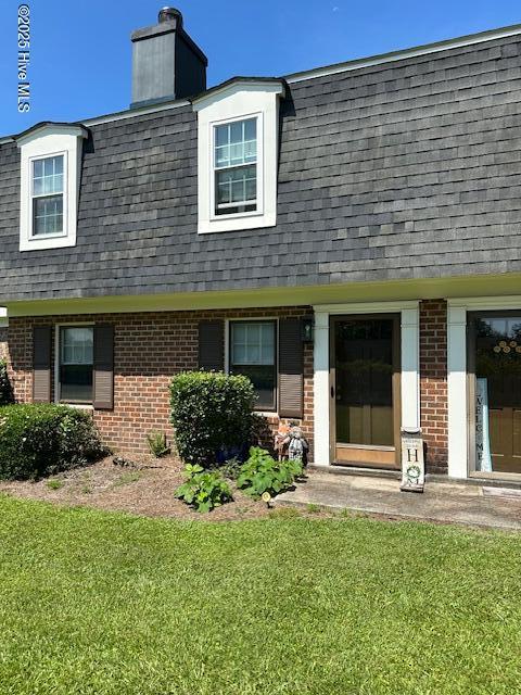7 Scott St, Greenville, NC 27858 - view of front of house with roof with shingles, brick siding, mansard roof, and a front lawn