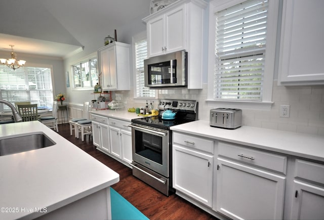 4875 Frasier Cir, Shallotte, NC 28470 - kitchen with appliances with stainless steel finishes, a chandelier, dark wood-type flooring, white cabinets, and backsplash