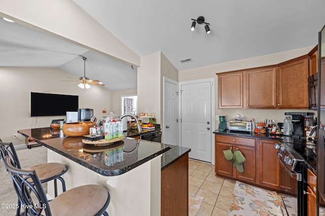 101 Falcon Landing Ct, New Bern, NC 28560 - kitchen featuring lofted ceiling, a ceiling fan, a kitchen breakfast bar, dark stone countertops, and brown cabinetry