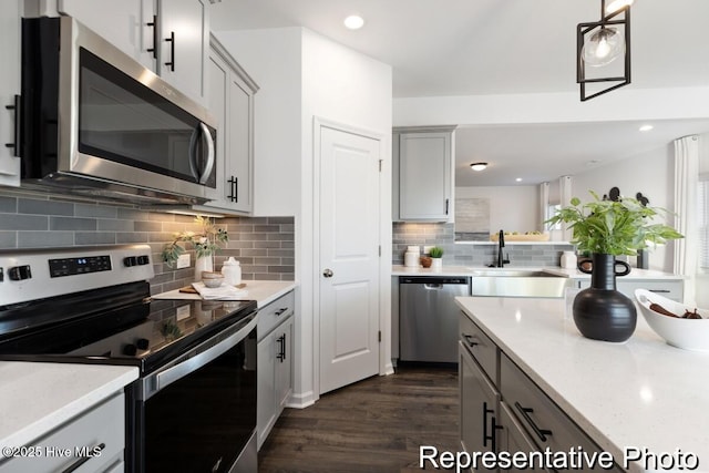 1664 Greenside Ct SW Unit 77, Ocean Isle Beach, NC 28469 - kitchen featuring appliances with stainless steel finishes, gray cabinets, backsplash, dark wood-type flooring, and hanging light fixtures