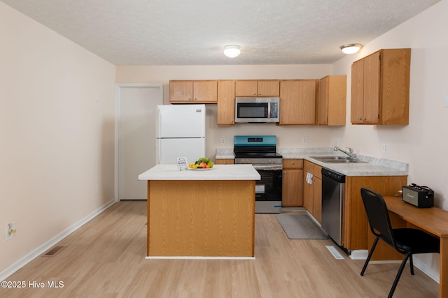 1901 Hess St, Wilmington, NC 28411 - kitchen featuring appliances with stainless steel finishes, light wood finished floors, light countertops, a center island, and a textured ceiling