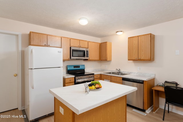 1901 Hess St, Wilmington, NC 28411 - kitchen with stainless steel appliances, light wood-style floors, light countertops, a center island, and a textured ceiling