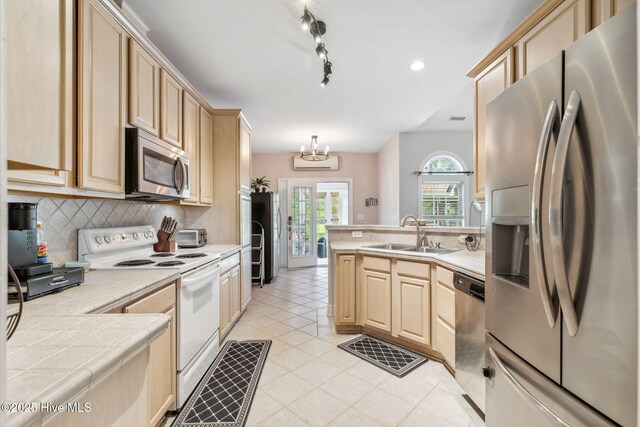 820 Jackeys Creek Ln SE, Leland, NC 28451 - kitchen with appliances with stainless steel finishes, light brown cabinets, tile counters, a peninsula, and decorative backsplash