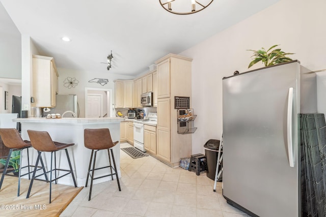 820 Jackeys Creek Ln SE, Leland, NC 28451 - kitchen featuring appliances with stainless steel finishes, light brown cabinetry, a breakfast bar, a peninsula, and light countertops