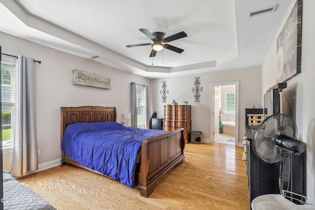 820 Jackeys Creek Ln SE, Leland, NC 28451 - bedroom featuring light wood-type flooring, a raised ceiling, ensuite bath, and ceiling fan
