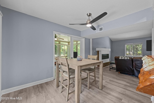 120 Croatan Ln, New Bern, NC 28562 - dining room with light wood-type flooring, a glass covered fireplace, a ceiling fan, and a textured ceiling