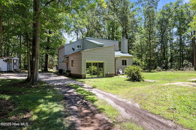 120 Croatan Ln, New Bern, NC 28562 - view of side of property featuring a chimney, a lawn, driveway, and a storage shed