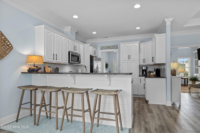 505 Davidson Dr, Newport, NC 28570 - kitchen featuring appliances with stainless steel finishes, a peninsula, white cabinetry, a kitchen bar, and crown molding