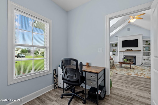 505 Davidson Dr, Newport, NC 28570 - office area with vaulted ceiling, wood finished floors, a ceiling fan, a fireplace with raised hearth, and built in shelves