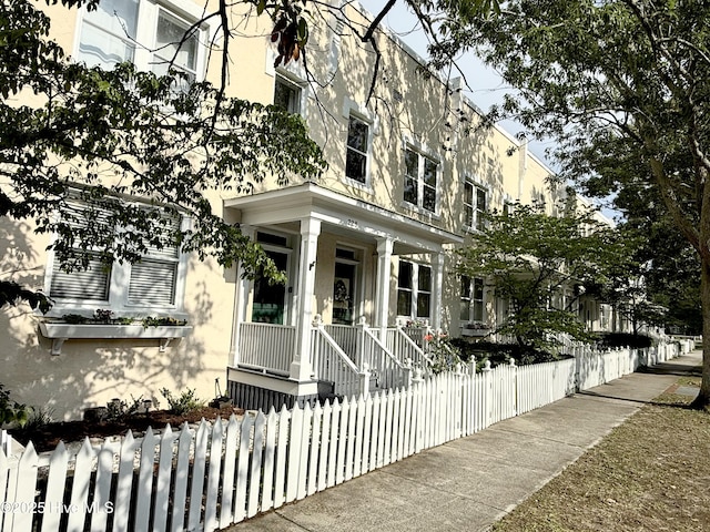 228 Mcrae St, Wilmington, NC 28401 - view of front facade featuring stucco siding, a fenced front yard, and covered porch