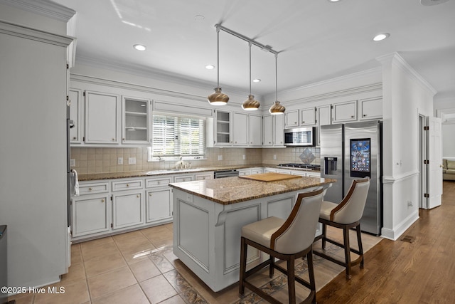 3902 Kipling Ct, Greenville, NC 27834 - kitchen with stainless steel appliances, a center island, decorative backsplash, glass insert cabinets, and ornamental molding
