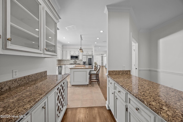 3902 Kipling Ct, Greenville, NC 27834 - kitchen featuring appliances with stainless steel finishes, dark stone countertops, glass insert cabinets, light wood finished floors, and backsplash