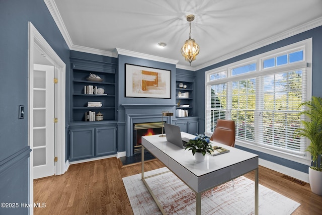 3902 Kipling Ct, Greenville, NC 27834 - office area featuring a lit fireplace, ornamental molding, dark wood-style floors, a chandelier, and built in shelves