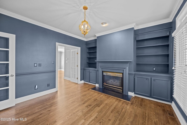 3902 Kipling Ct, Greenville, NC 27834 - unfurnished living room featuring built in shelves, a glass covered fireplace, crown molding, a chandelier, and wood finished floors