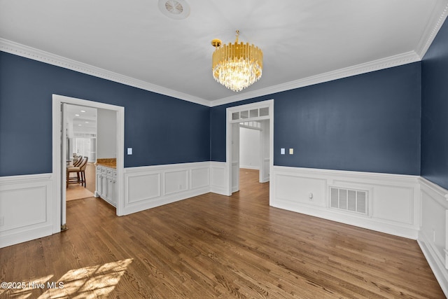 3902 Kipling Ct, Greenville, NC 27834 - empty room featuring a chandelier, a wainscoted wall, ornamental molding, and wood finished floors