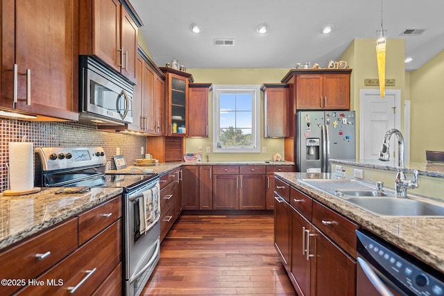9406 Voyagers Way, Wilmington, NC 28412 - kitchen with appliances with stainless steel finishes, dark wood finished floors, decorative backsplash, glass insert cabinets, and hanging light fixtures