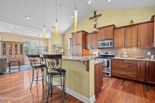 9406 Voyagers Way, Wilmington, NC 28412 - kitchen featuring stainless steel appliances, a kitchen breakfast bar, dark wood-style floors, light stone countertops, and a kitchen island