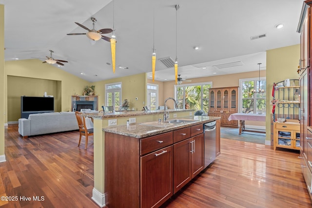 9406 Voyagers Way, Wilmington, NC 28412 - kitchen featuring stainless steel dishwasher, ceiling fan, a fireplace, open floor plan, and wood-type flooring