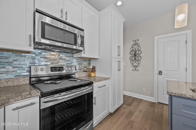 4340 Island Dr, North Topsail Beach, NC 28460 - kitchen with stainless steel appliances, light stone counters, wood finished floors, white cabinets, and backsplash
