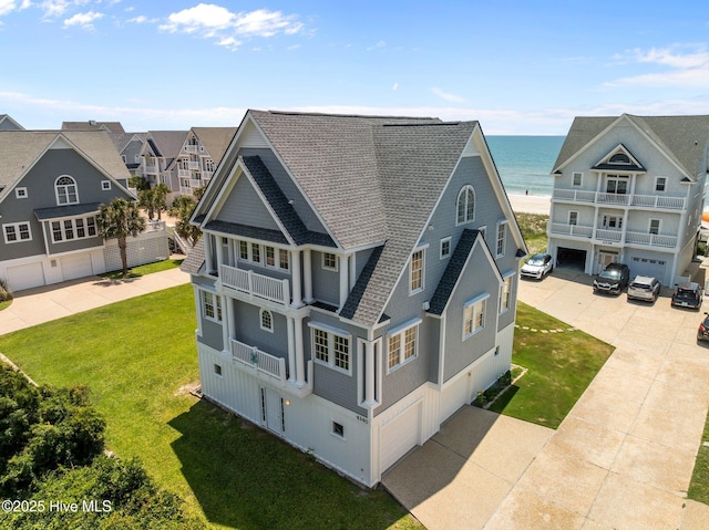 4340 Island Dr, North Topsail Beach, NC 28460 - back of house with a balcony, roof with shingles, a yard, concrete driveway, and a water view