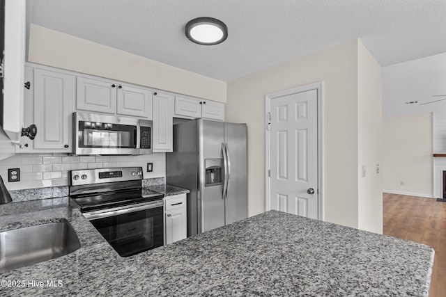 5601 W Chop Way, Wilmington, NC 28412 - kitchen with stainless steel appliances, wood finished floors, white cabinetry, dark stone countertops, and backsplash