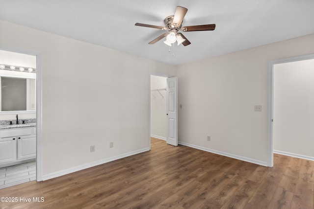 5601 W Chop Way, Wilmington, NC 28412 - unfurnished bedroom featuring a walk in closet, wood finished floors, a closet, connected bathroom, and ceiling fan