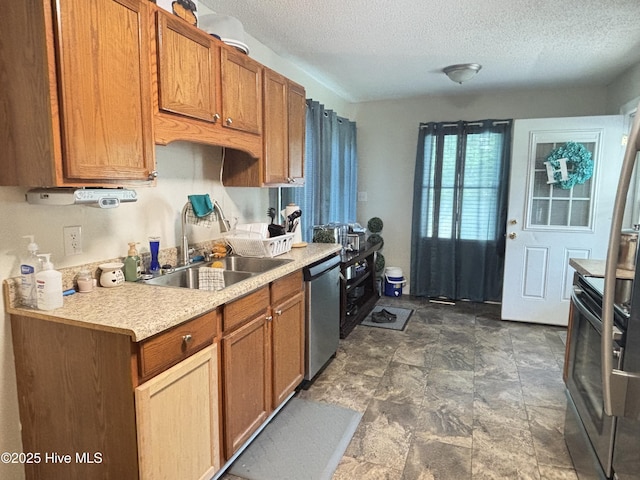 103 Jay Trl, Murfreesboro, NC 27855 - kitchen featuring appliances with stainless steel finishes, a textured ceiling, light countertops, brown cabinetry, and stone finish floors