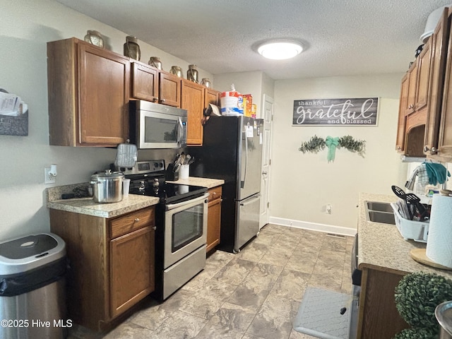 103 Jay Trl, Murfreesboro, NC 27855 - kitchen with stainless steel appliances, light countertops, a textured ceiling, and brown cabinetry