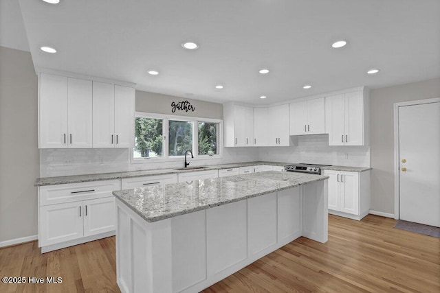 108 Sound View Dr, Hampstead, NC 28443 - kitchen featuring tasteful backsplash, white cabinetry, light wood-style floors, a center island, and recessed lighting