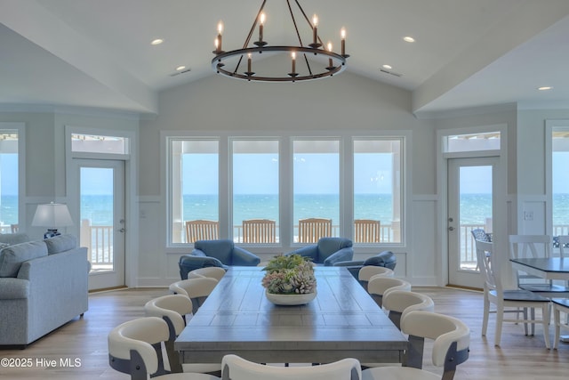 1326 New River Inlet Rd, North Topsail Beach, NC 28460 - dining room with a decorative wall, a wainscoted wall, light wood-style floors, lofted ceiling, and a chandelier