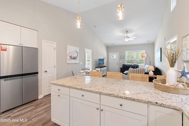 109 SW 17th St, Oak Island, NC 28465 - kitchen with freestanding refrigerator, light wood-style flooring, white cabinetry, ceiling fan, and open floor plan